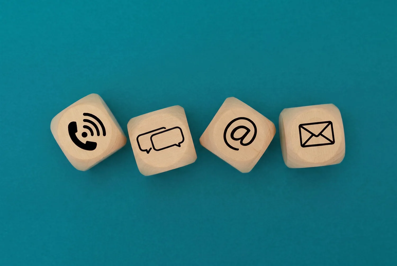 Quatre cubes en bois marqués d’un téléphone, de bulles de discussion, d’une arobase et d’une enveloppe