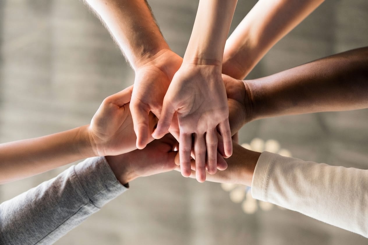 Les mains de plusieurs personnes posées les unes sur les autres, en signe d’union